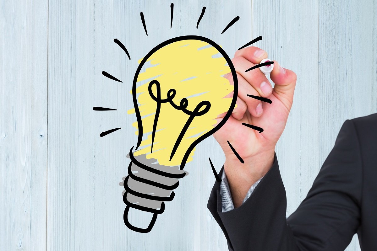 Composite of image of a hand drawing a light bulb on a board